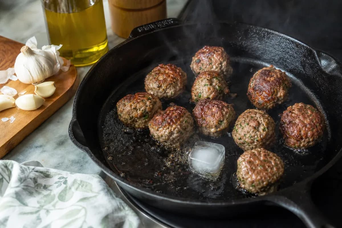 Editorial photo: The Ice-Cube Searing Trick for Juicy Meatballs (tips tricks tip) — realistic home-kitchen scene with visible tools and ingredients in natural l