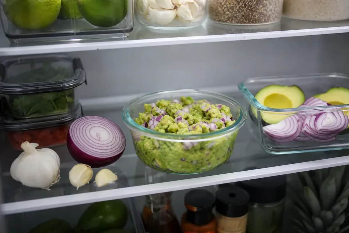 Halved avocados with lemon and plastic wrap on a cutting board to slow browning