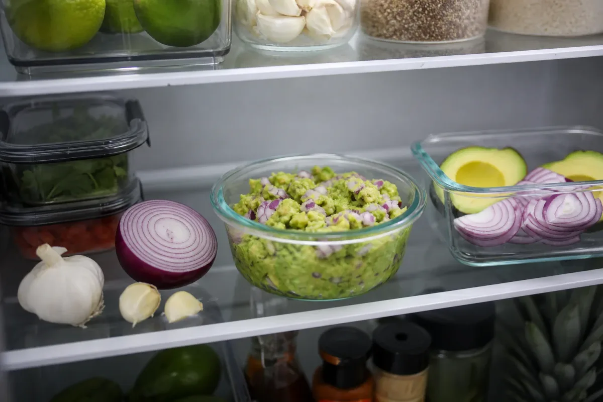 Halved avocados with lemon and plastic wrap on a cutting board to slow browning