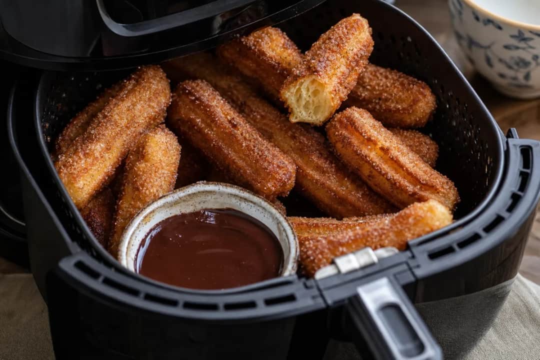 Plated air fryer churros dusted with cinnamon sugar, served with a chocolate dipping sauce.