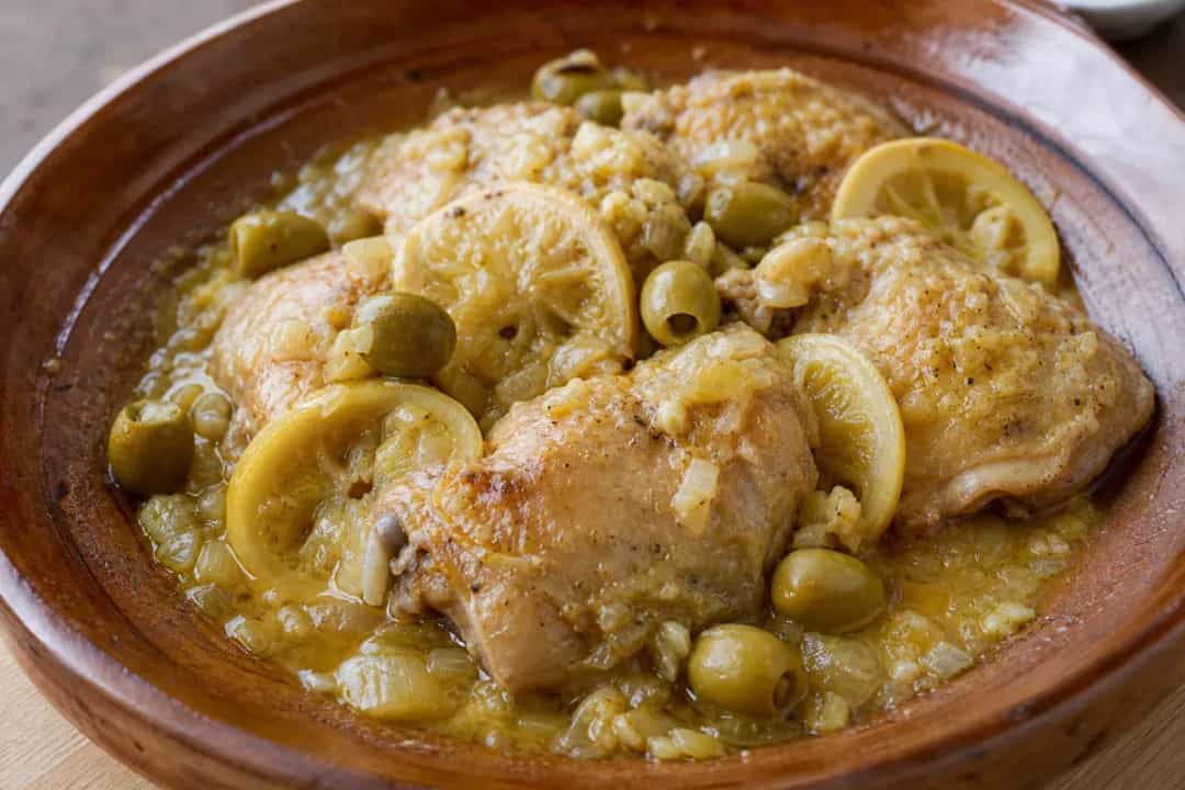 A vibrant plate of Algerian Chicken Tajine with olives, lemon, and tender chicken, garnished with fresh herbs.