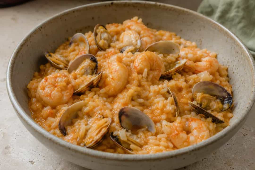 A vibrant dish of Portuguese seafood rice with shrimp, clams, and herbs garnished elegantly.