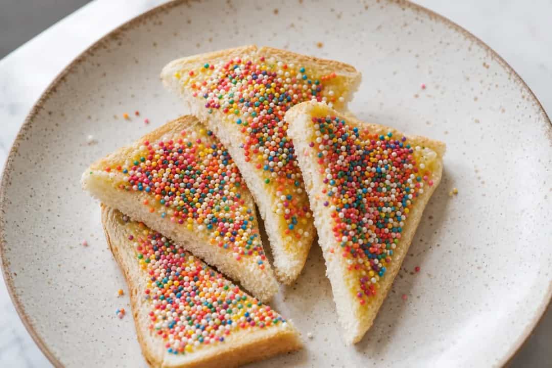Slices of white bread spread with butter and topped with vibrant sprinkles on a plate.