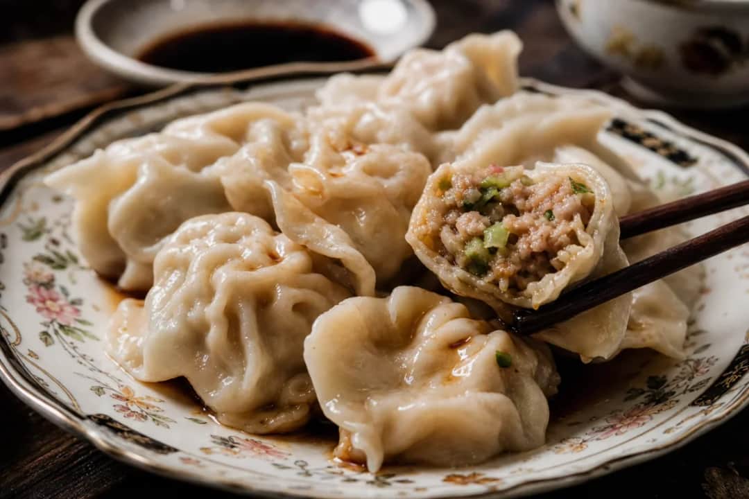 Steamed pork and veggie dumplings served with soy sauce, showcasing tender wrappers and juicy filling.