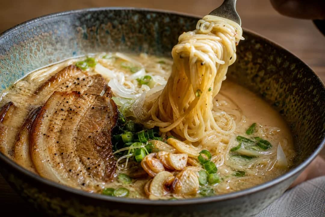Bowl of Tonkotsu Ramen topped with sliced pork belly and green onions in a rich broth