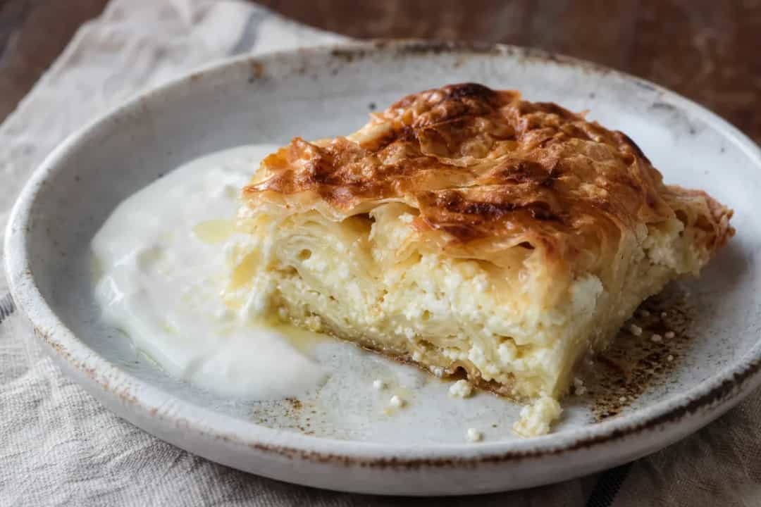 Golden-brown Serbian Gibanica pie with crispy layers and feta cheese filling, beautifully plated.