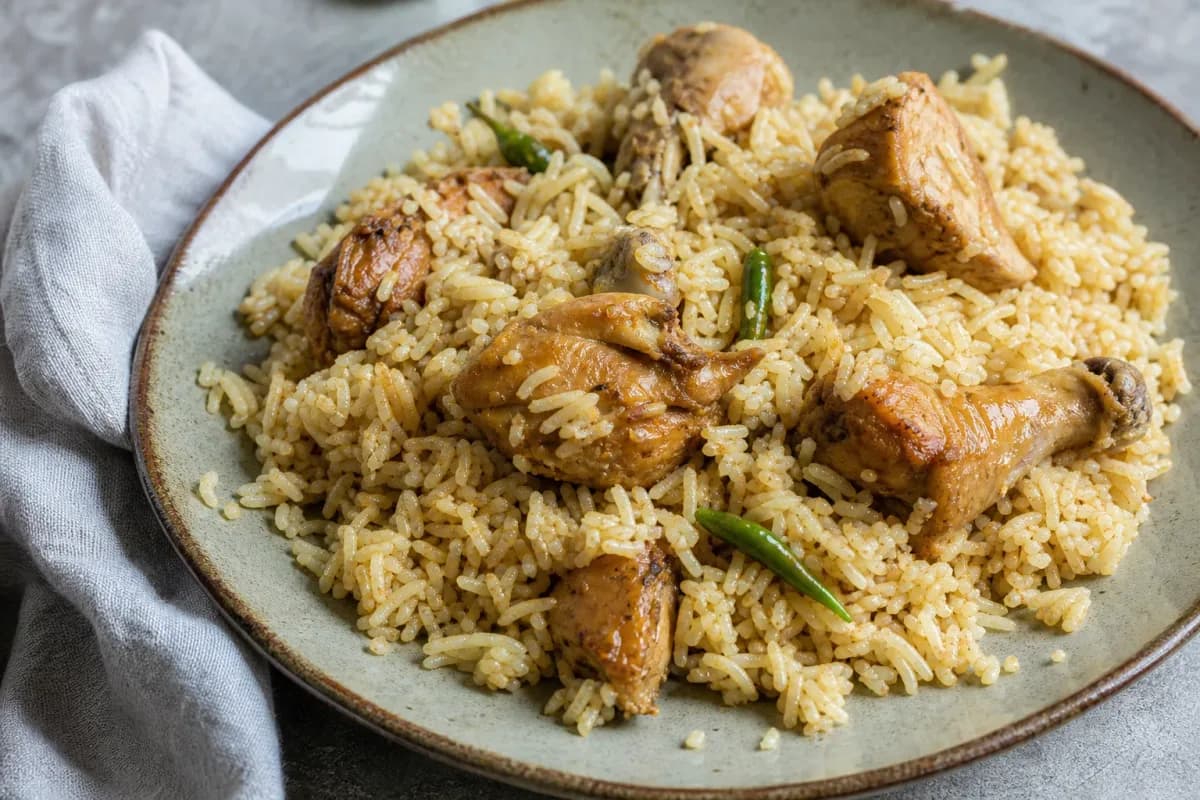 A vibrant plate of Morog Polao featuring tender chicken pieces atop fluffy fragrant rice garnished with fresh herbs.