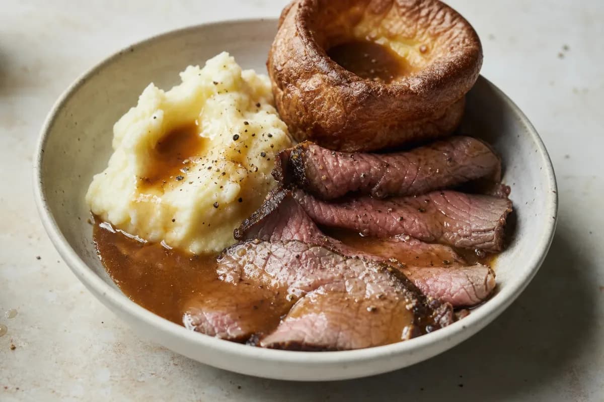 Plated roast beef with crispy Yorkshire pudding, served with gravy and vegetables.