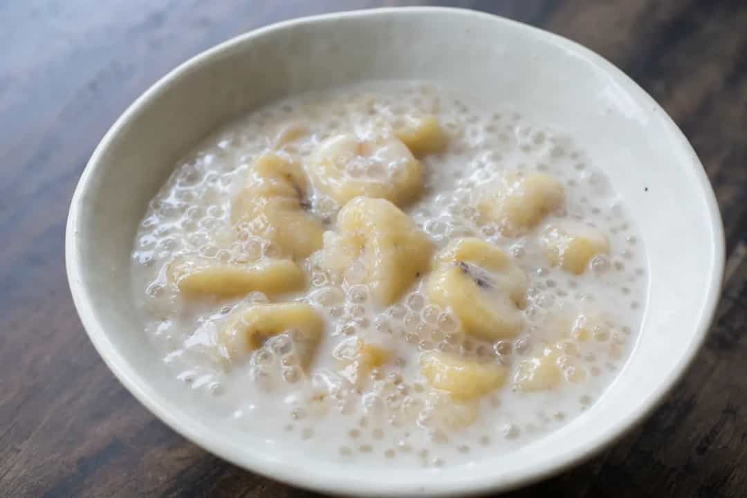 Creamy tapioca pudding layered with sliced bananas and coconut milk, garnished with toasted coconut flakes.