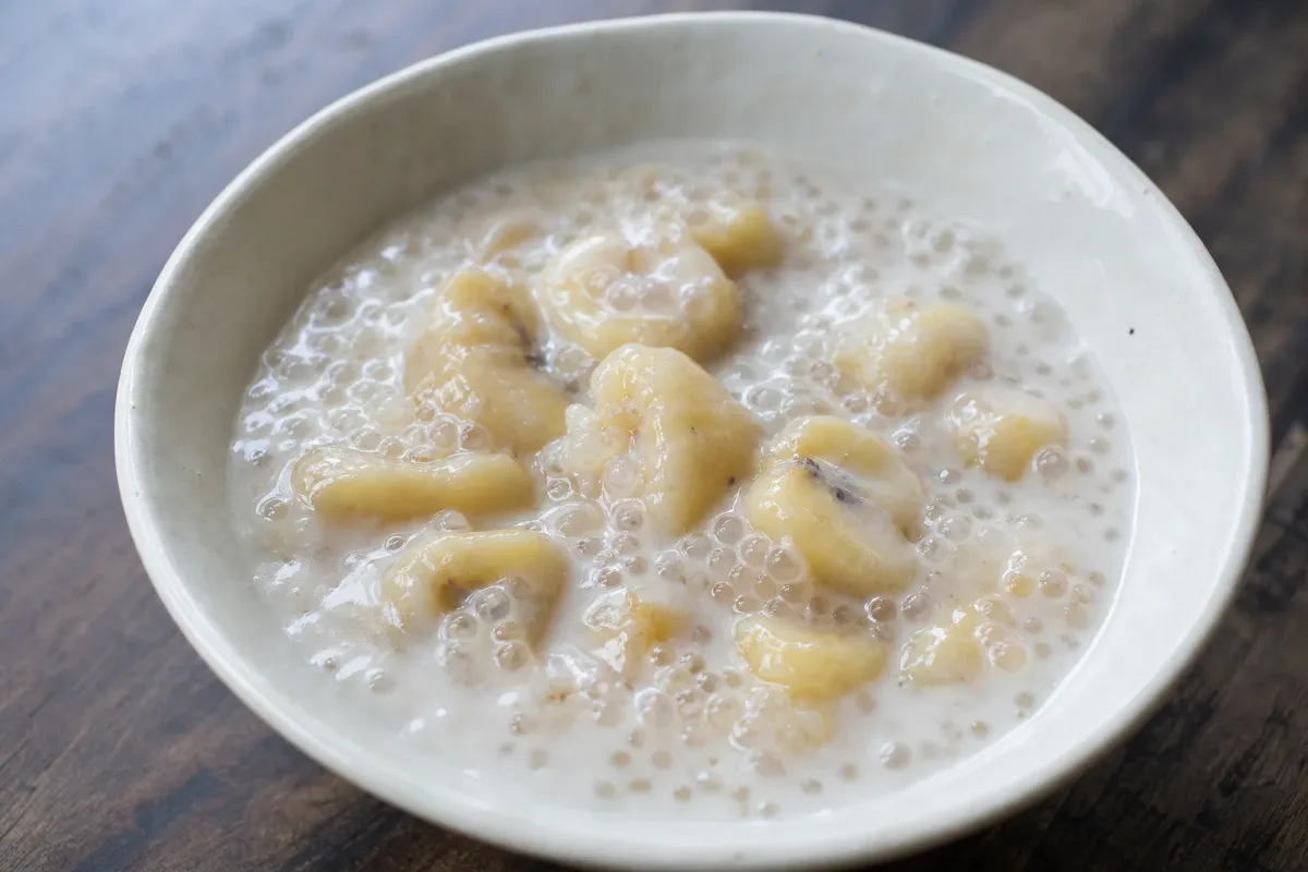 Creamy tapioca pudding layered with sliced bananas and coconut milk, garnished with toasted coconut flakes.