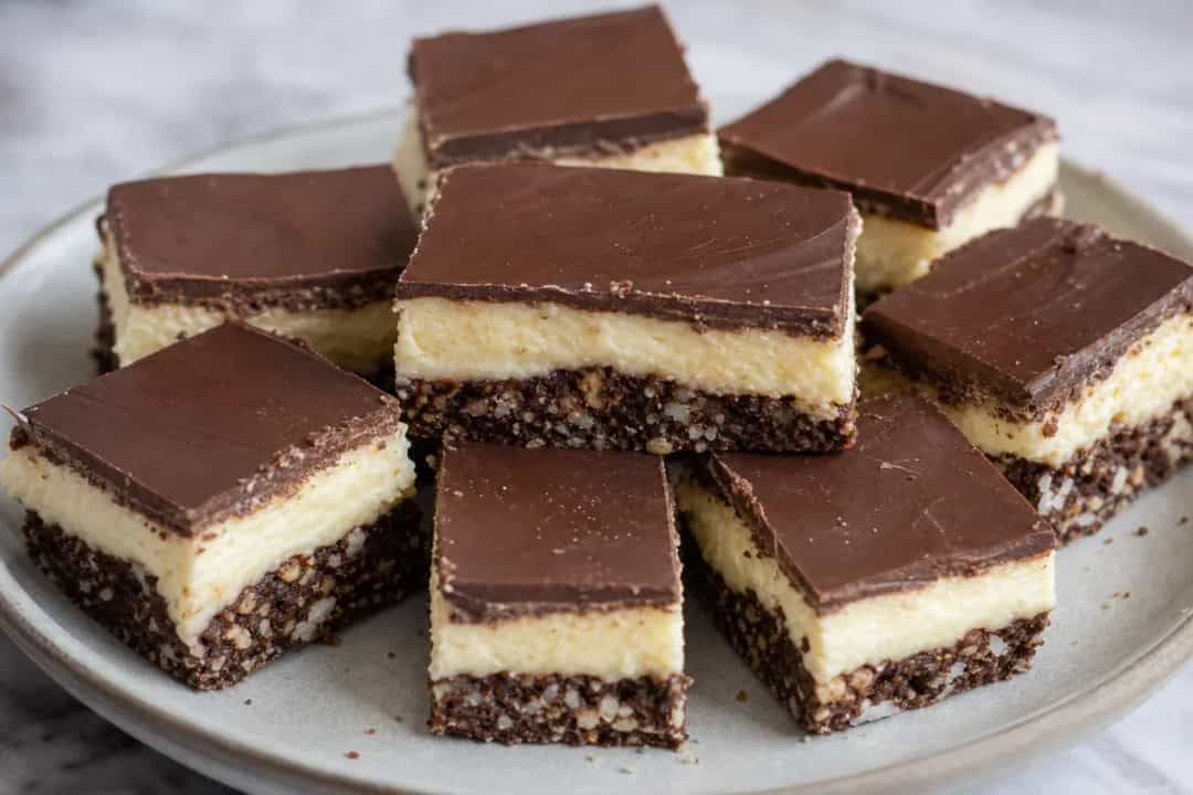 Layered Nanaimo bars showcasing chocolate, custard, and crumbly base.