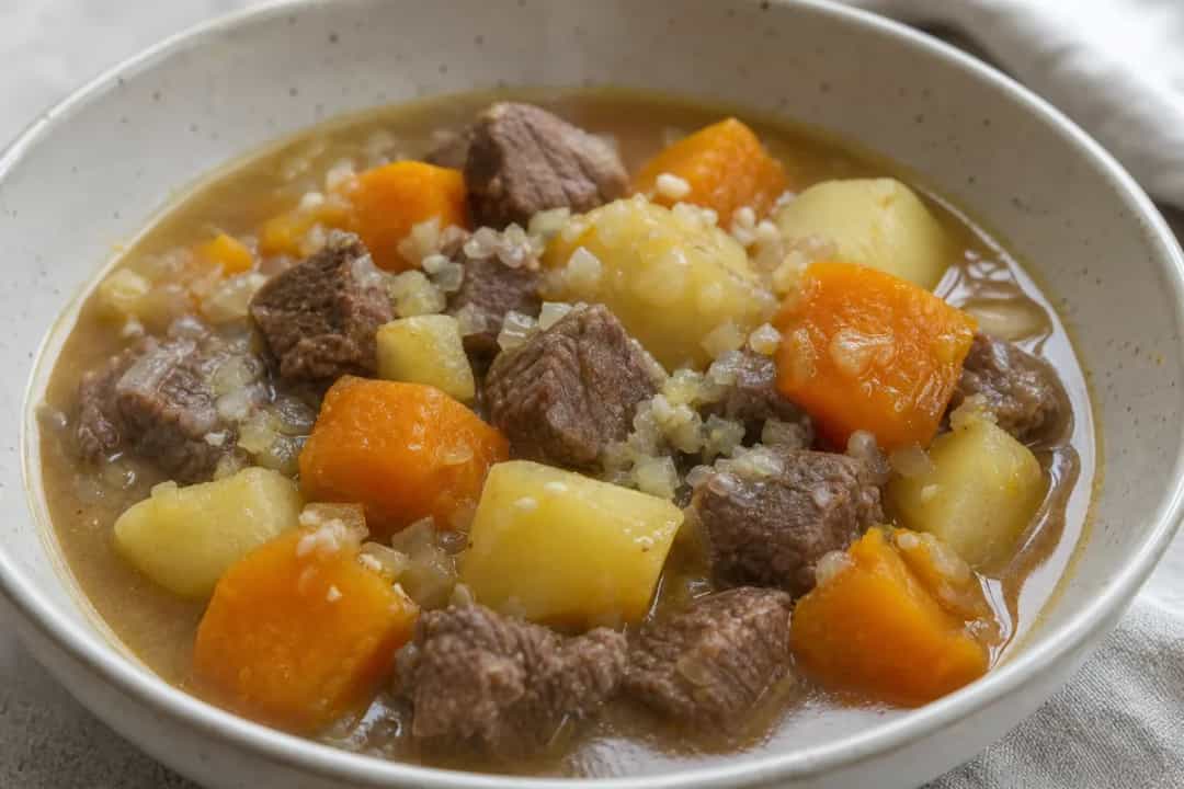 A warm bowl of Chilean cazuela de vacuno with chunks of beef, pumpkin, and potatoes in rich broth.