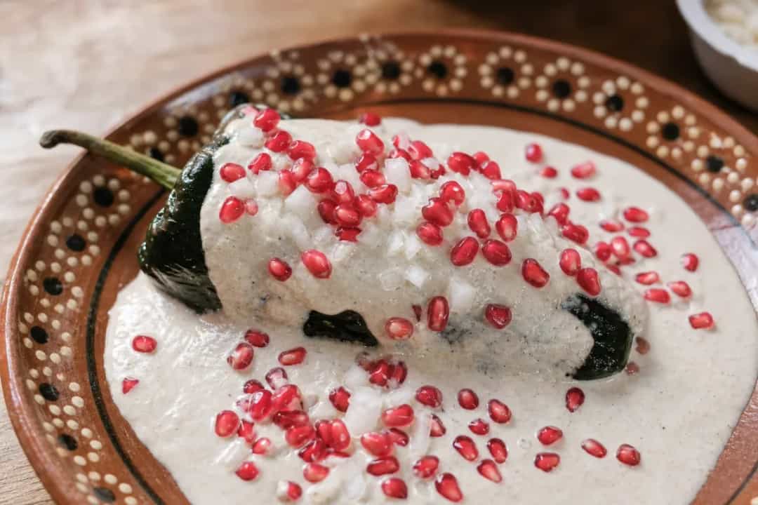 Stuffed poblano peppers topped with creamy walnut sauce and vibrant pomegranate seeds.