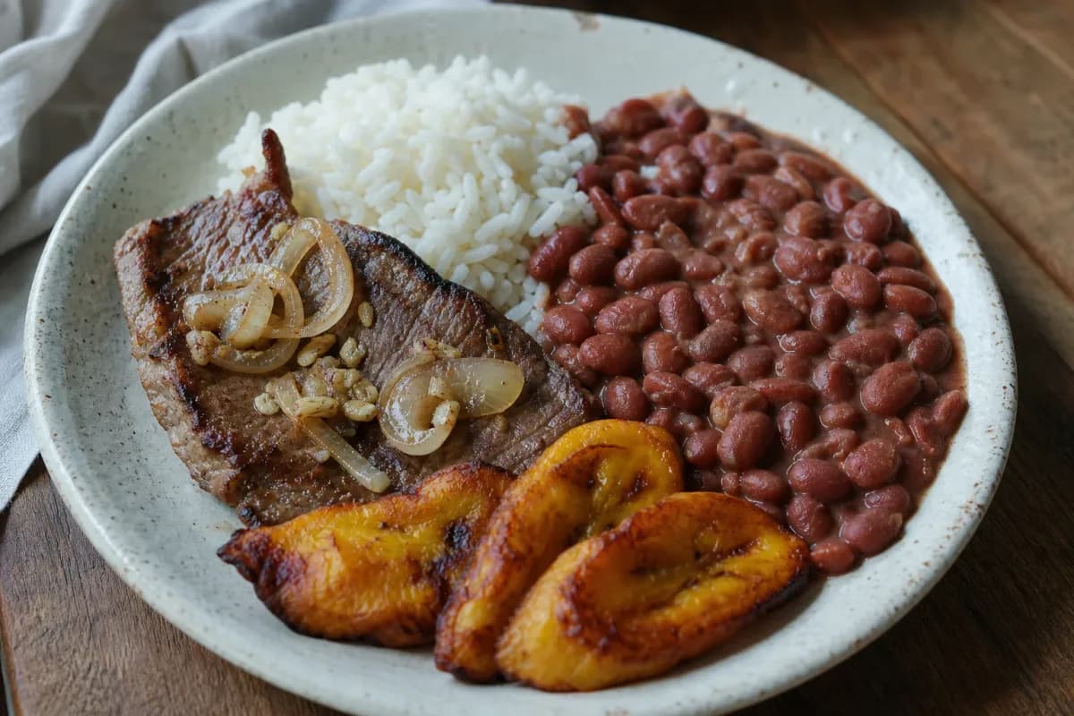 A vibrant platter of Colombian Bandeja Paisa with rice, beans, beef, and fried plantains.