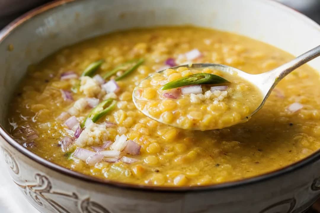 Creamy Sri Lankan Dhal Curry served with rice and garnished with fresh herbs.