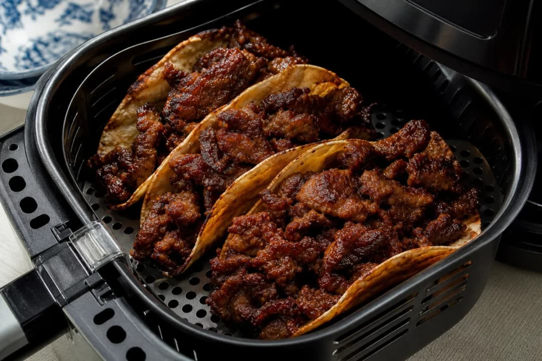 Close-up of Crispy Air Fryer Korean Bulgogi Tacos with Spicy Slaw, inside an open air fryer basket with crispy golden browning (dinner recipe)