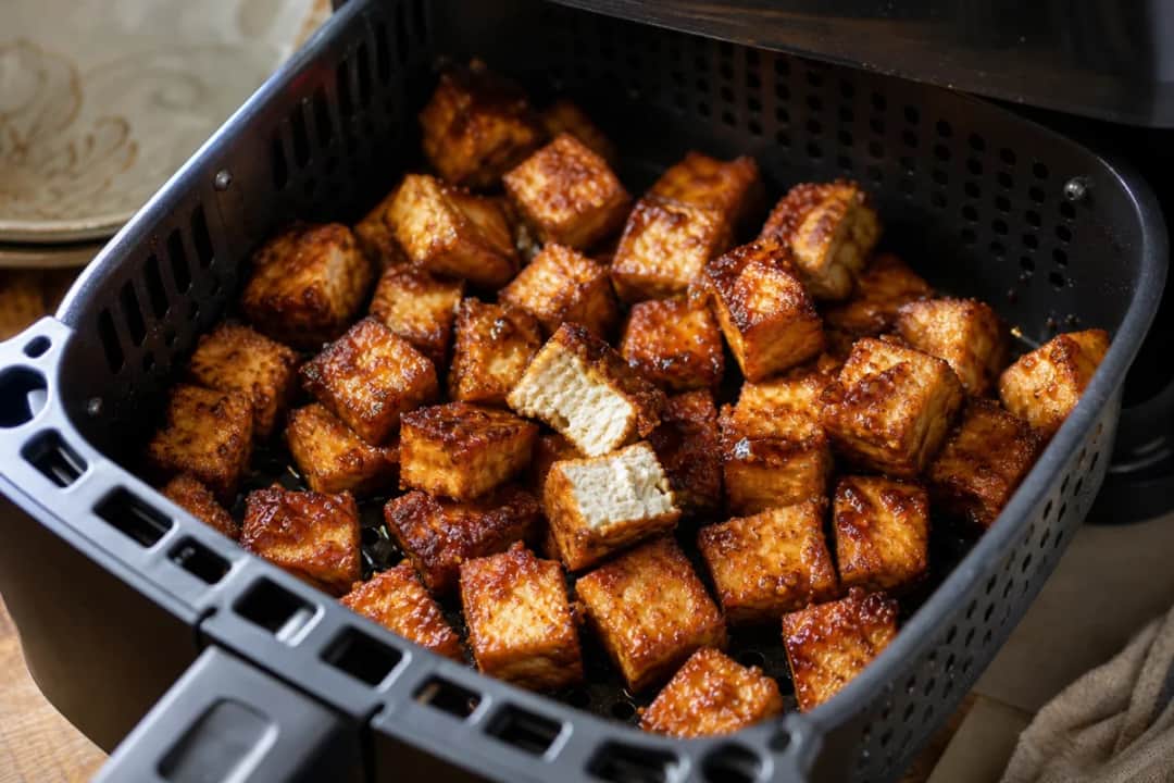 Crispy air fryer tofu bites drizzled with sweet sesame soy glaze and garnished with sesame seeds.