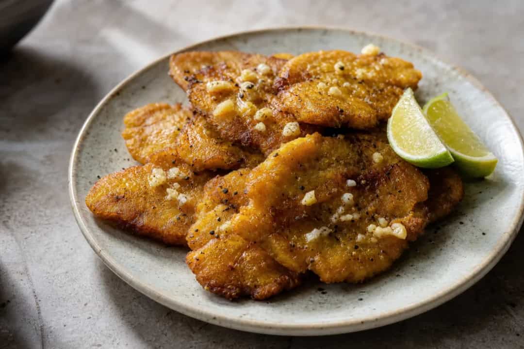 Golden brown twice-fried plantains served with garlic dipping sauce and garnished with fresh cilantro.