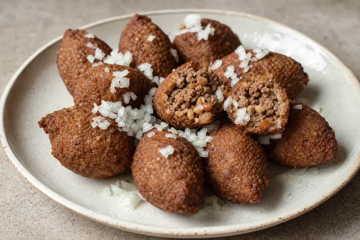 Golden-brown kibbeh with a crispy exterior, filled with spiced beef and pine nuts, garnished with parsley.