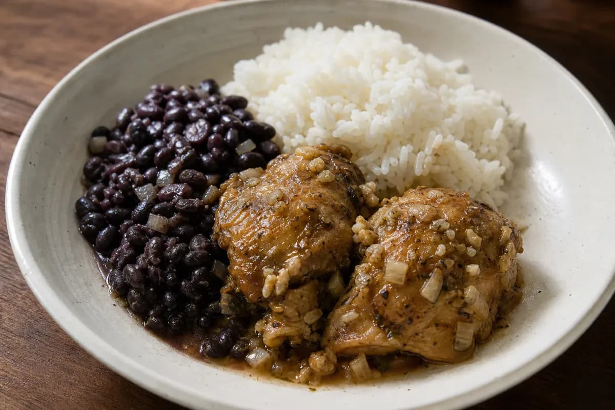 Colorful plated La Bandera with tender chicken, white rice, and black beans garnished with fresh herbs.