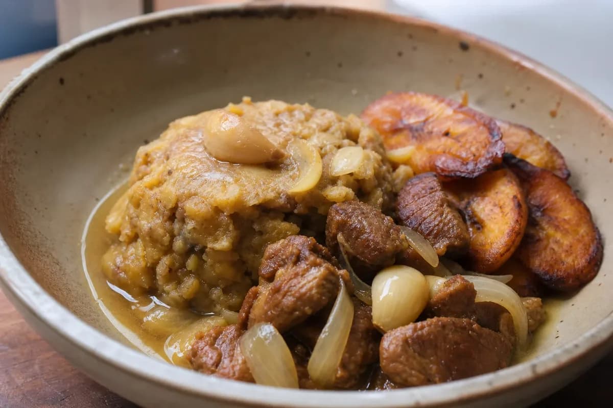 Plated Dominican mofongo with garlic pork, crispy fried plantains, and fresh herbs.