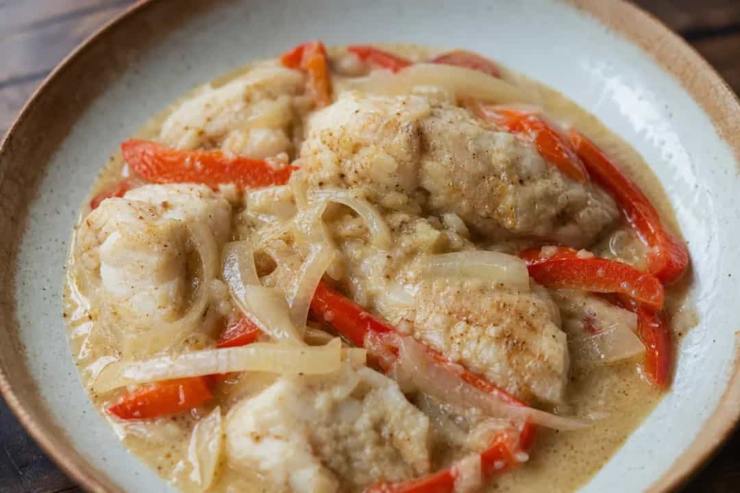 Plated Dominican Pescado con Coco with tender fish in creamy coconut sauce and colorful peppers.