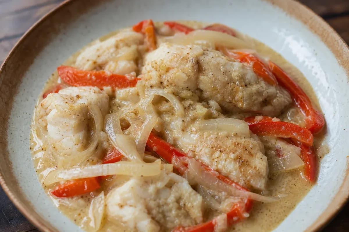 Plated Dominican Pescado con Coco with tender fish in creamy coconut sauce and colorful peppers.