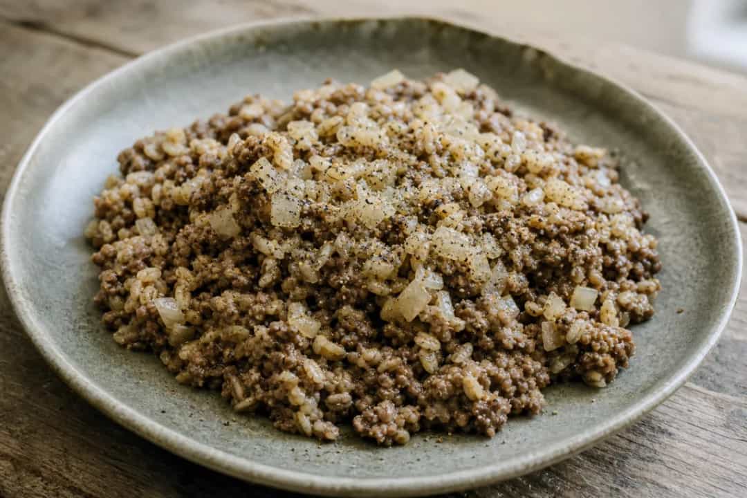 Plated Scottish haggis on a bed of mashed potatoes, garnished with herbs.