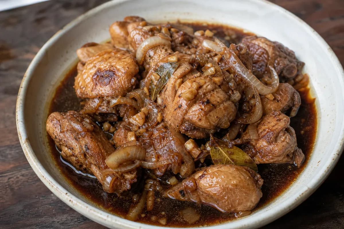 Tender chicken pieces coated in a rich soy-vinegar sauce, garnished with garlic and herbs.