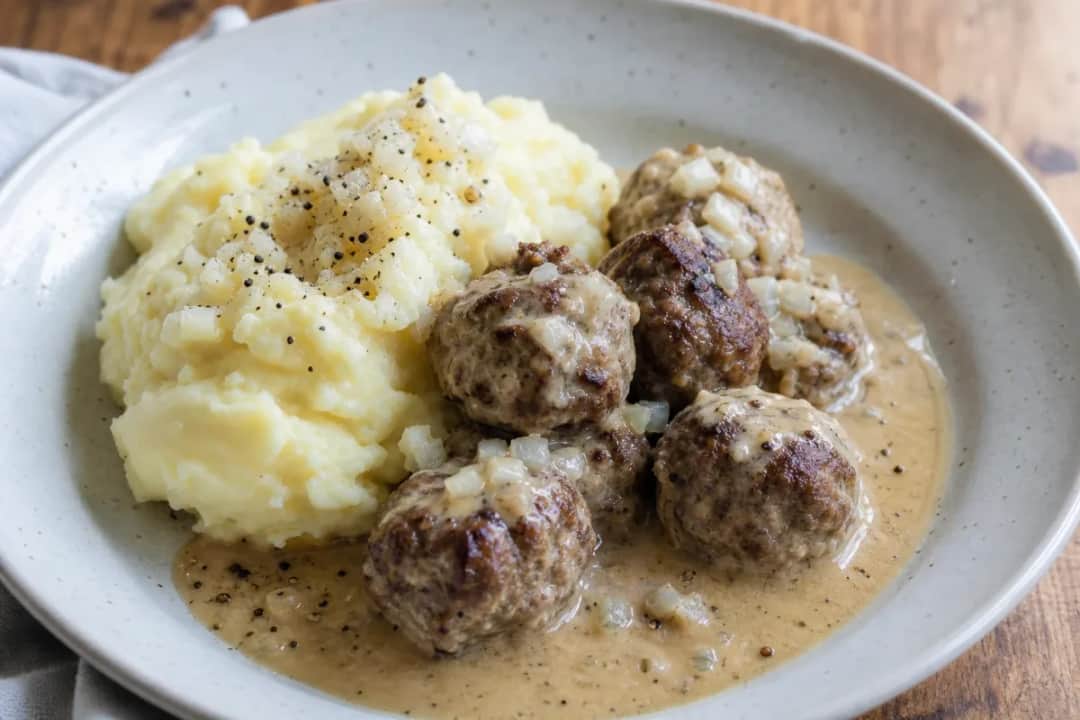 Tender Finnish meatballs smothered in creamy sauce, served with fluffy mashed potatoes and garnished with parsley.