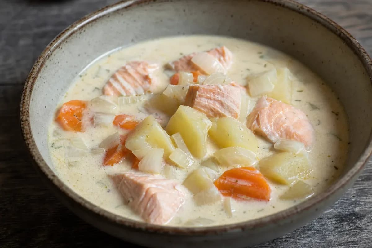 Creamy Finnish salmon soup with tender potatoes, carrots, and fresh herbs garnished elegantly in a bowl.