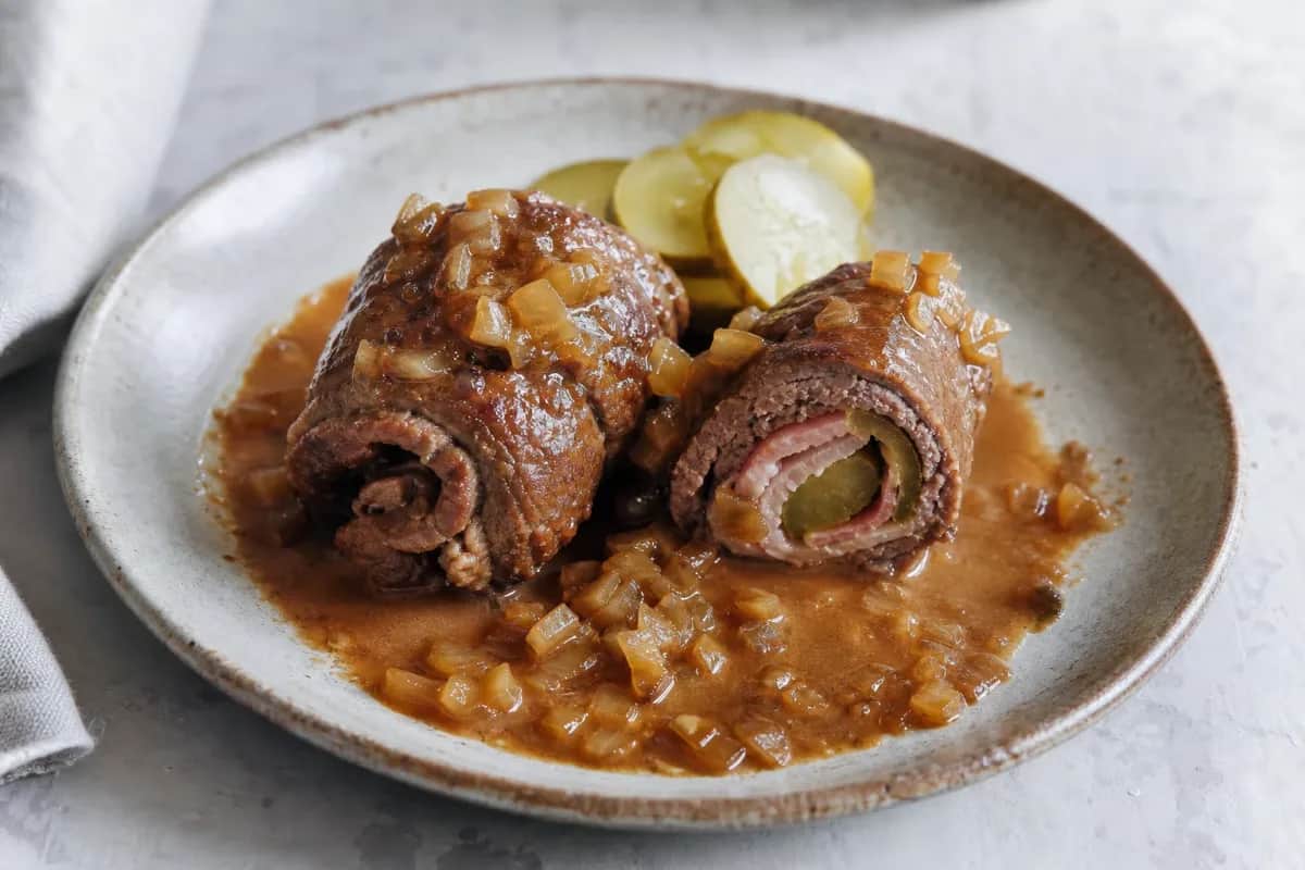 Tender beef rouladen filled with bacon and pickles, served with rich onion gravy.