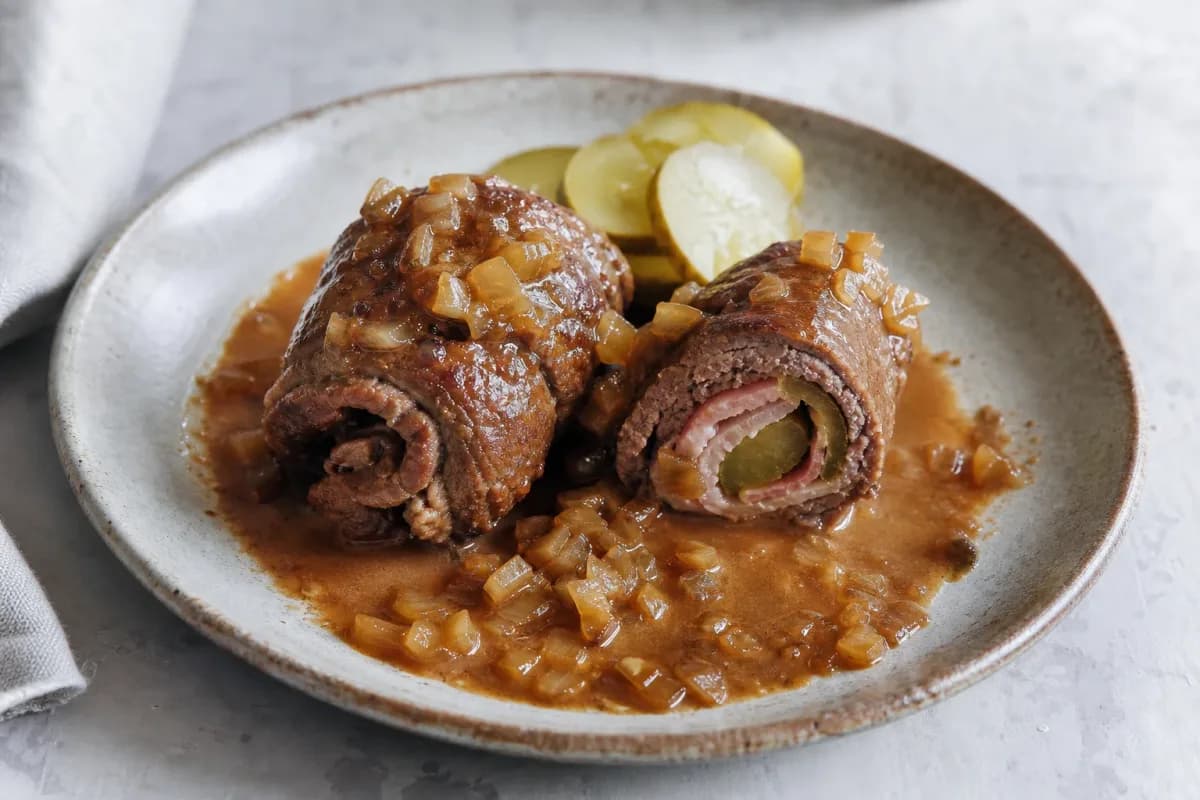 Tender beef rouladen filled with bacon and pickles, served with rich onion gravy.