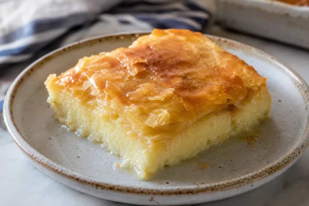 Layers of golden phyllo pastry with creamy custard, drizzled in syrup and garnished with lemon zest.
