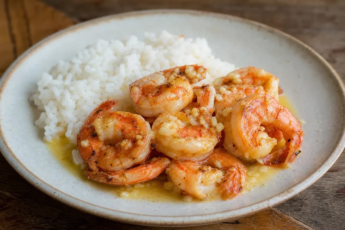 Plated Hawaiian garlic shrimp with rice, garnished with parsley and lemon slices, showcasing a glossy sauce.