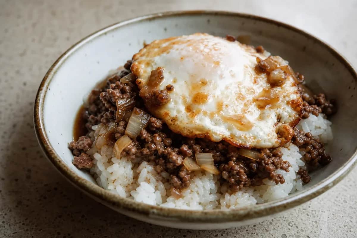 A hearty serving of Hawaiian loco moco with rice, a beef patty, brown gravy, and a perfectly fried egg on top.