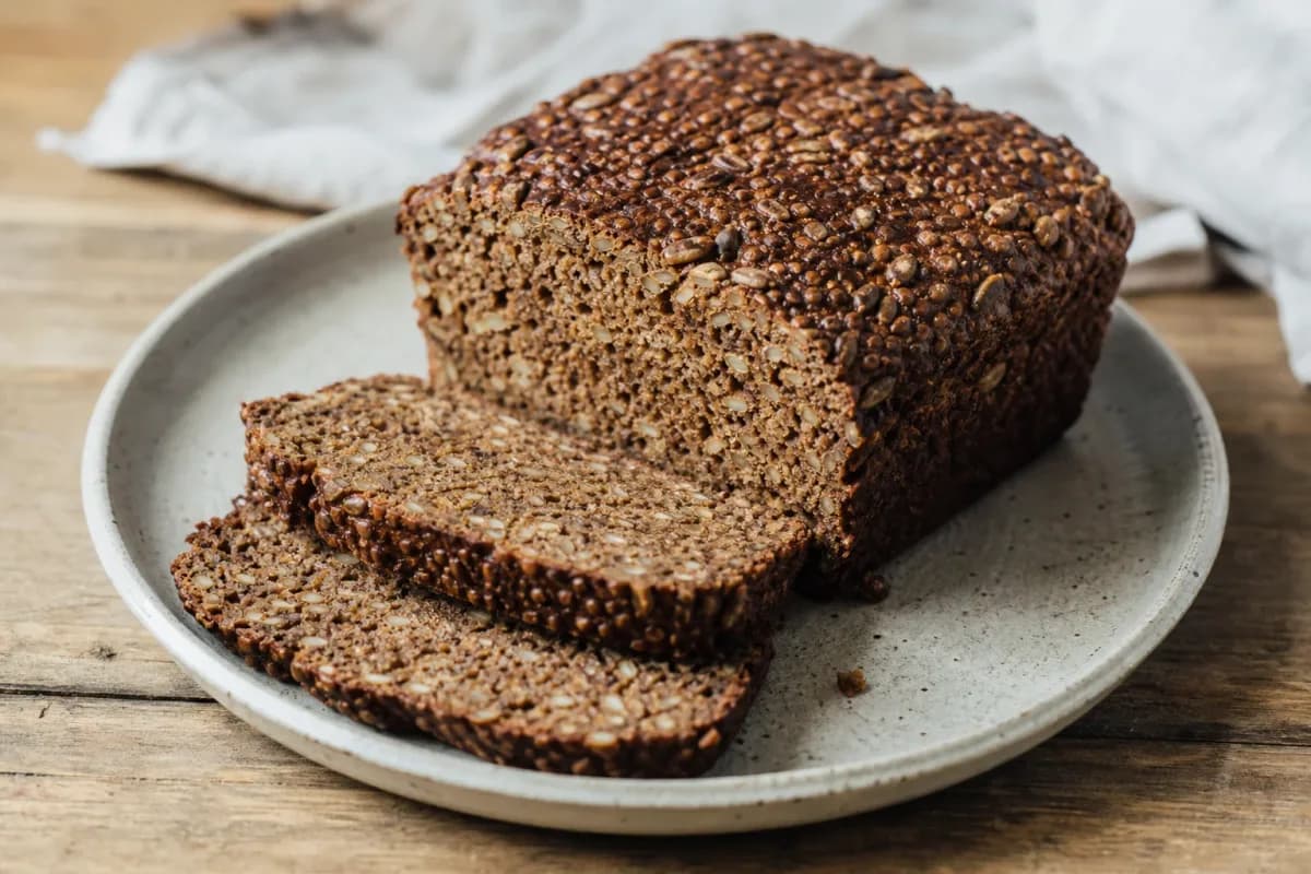 Sliced Danish Rugbrød showcasing the dense texture and seed toppings on a wooden board.