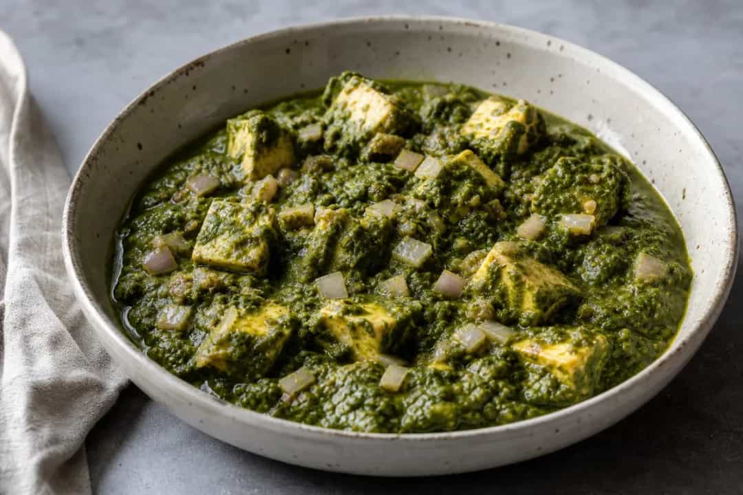 Vibrant green palak paneer served with soft paneer cubes and spices, garnished with cream.