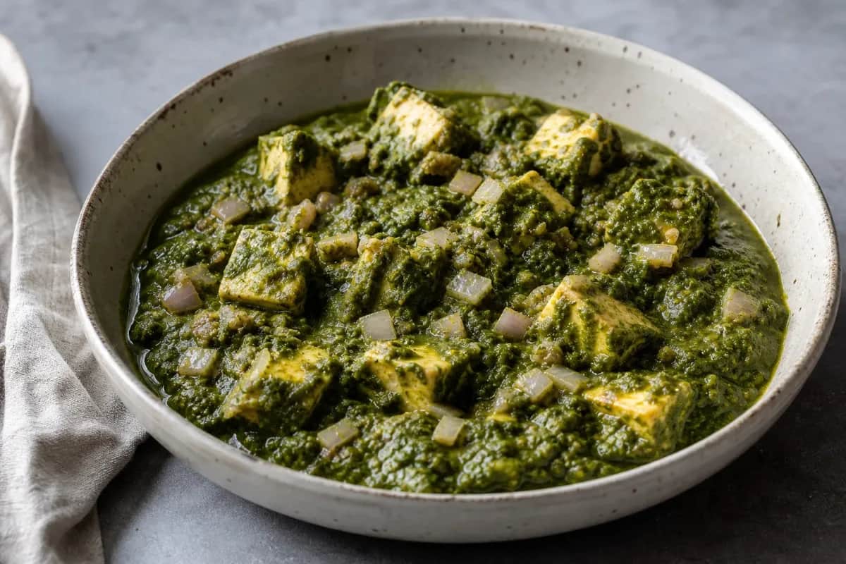 Vibrant green palak paneer served with soft paneer cubes and spices, garnished with cream.