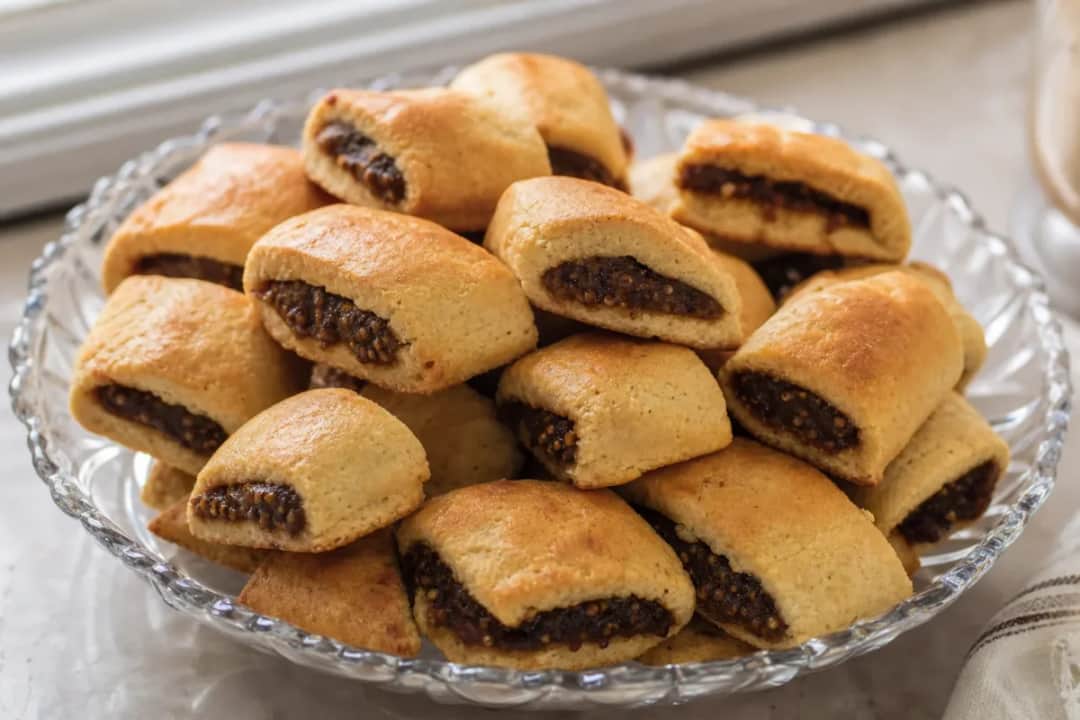Golden brown Iraqi kleicha cookies filled with sweet date paste, beautifully arranged on a plate.