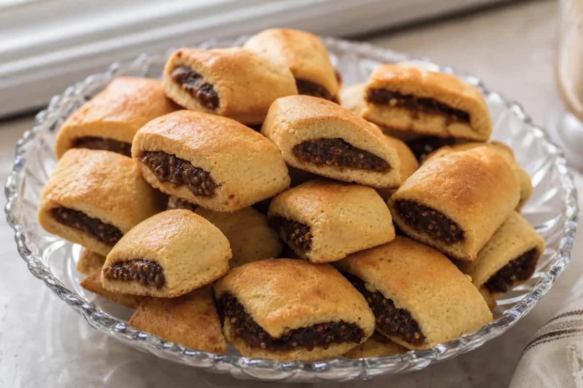 Golden brown Iraqi kleicha cookies filled with sweet date paste, beautifully arranged on a plate.