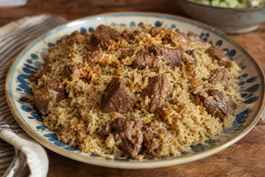 Plated Iraqi Quzi featuring tender lamb, fragrant rice, and colorful nuts and raisins garnished attractively.