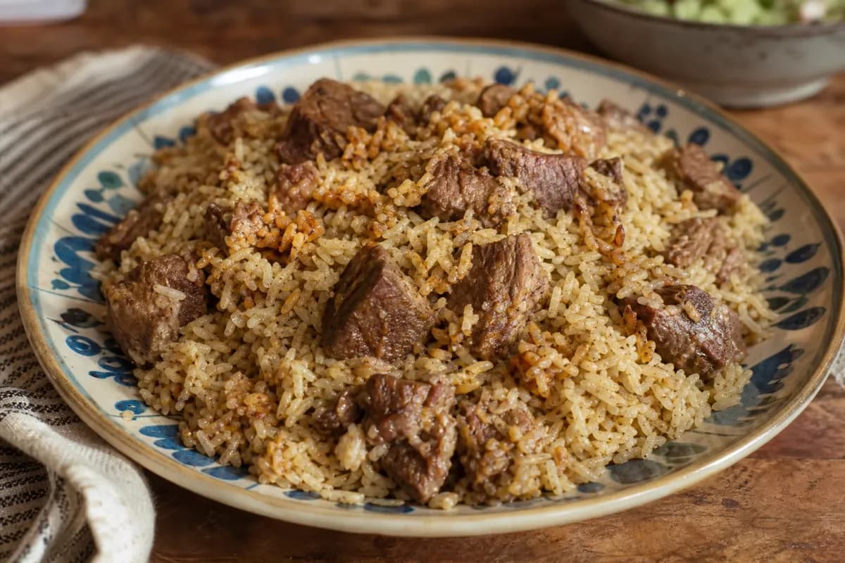 Plated Iraqi Quzi featuring tender lamb, fragrant rice, and colorful nuts and raisins garnished attractively.