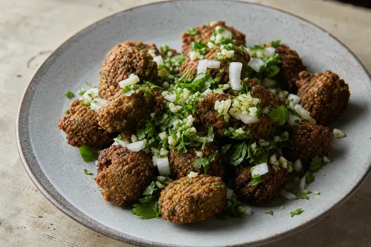 Golden-brown falafel balls served with crispy chickpeas, fresh herbs, and drizzled tahini sauce.