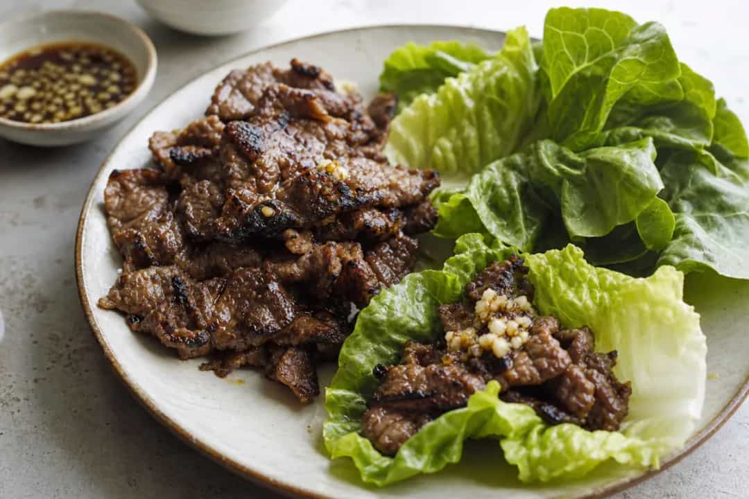 Tender bulgogi beef wrapped in crisp lettuce leaves, garnished with sesame seeds and green onions.