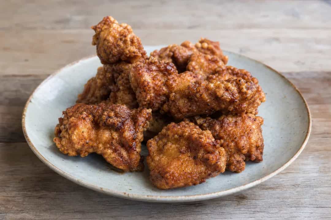 Golden crispy fried chicken pieces glazed with spicy gochujang sauce and garnished with sesame seeds.