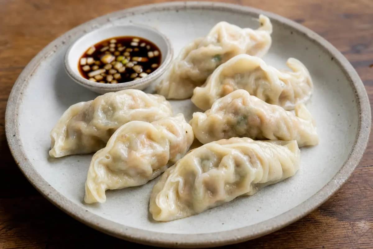 Plated Korean Mandu showcasing golden-brown dumplings, filled with pork and vegetables garnished with sesame seeds.