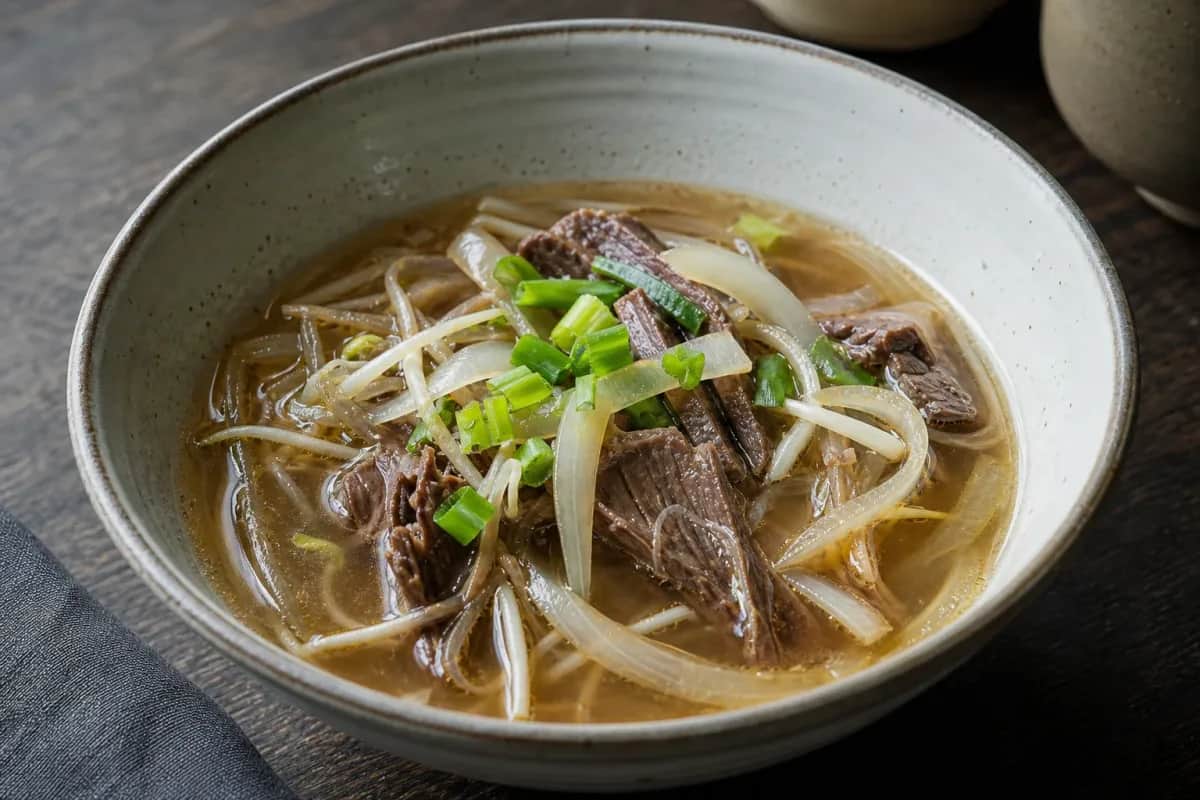A steaming bowl of Yukgaejang with spicy beef, vibrant vegetables, and garnished with green onions.