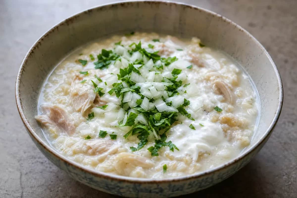 A warm bowl of Kurdish Mehir Soup garnished with fresh herbs and yogurt, rich in color and texture.