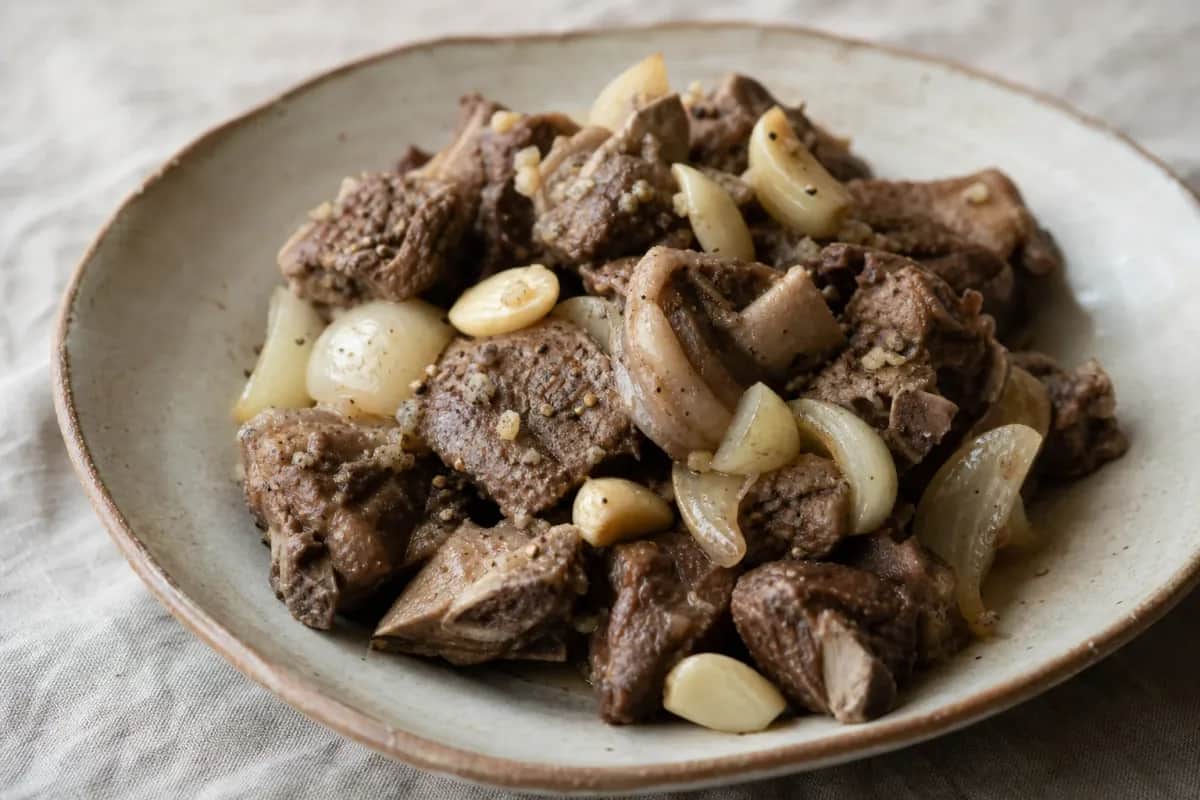 Tender slow-cooked lamb with spices, served with fresh vegetables on a rustic plate.